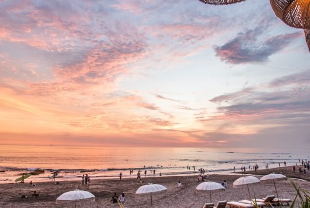white parasol and lounge near seashores